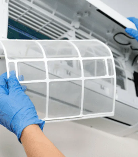 Gloved hands removing the filter from a split system indoor unit for cleaning