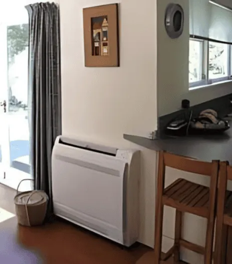 Floor mounted air conditioner installed under a window in a dining room